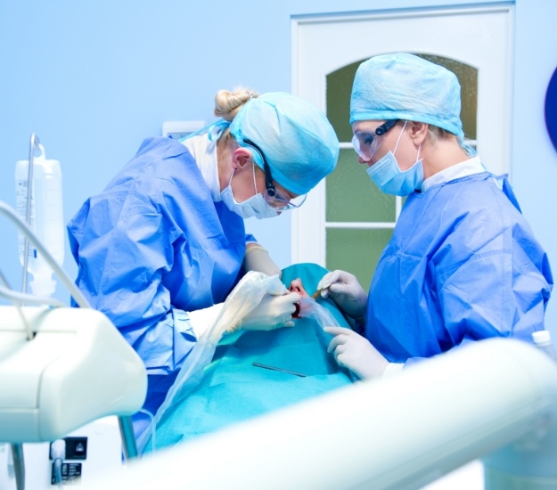 Two dental professionals performing dental implant surgery