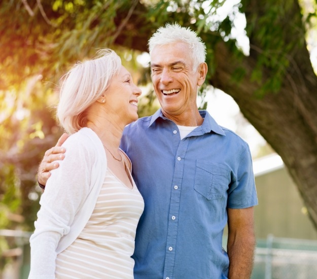 Senior man and woman hugging and laughing outdoors