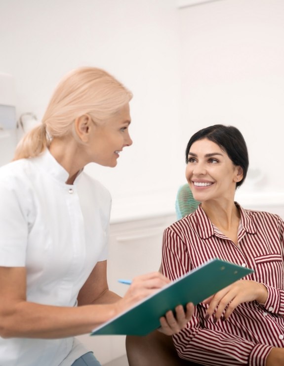 Woman talking with dental team member holding clipboard