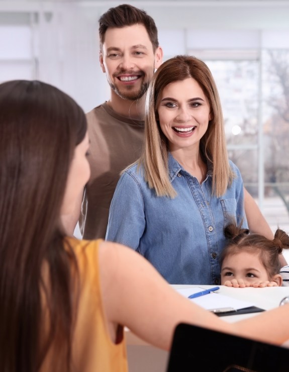 Family of three talking to dental office receptionist