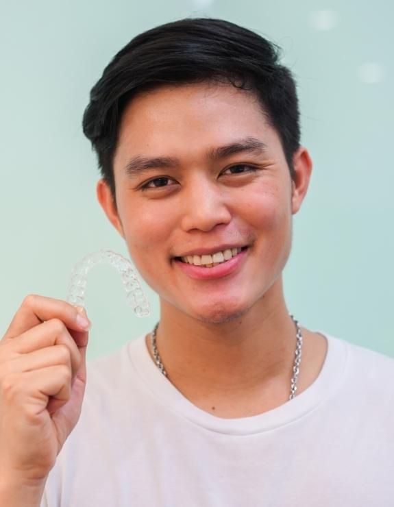 Young man holding an Invisalign aligner