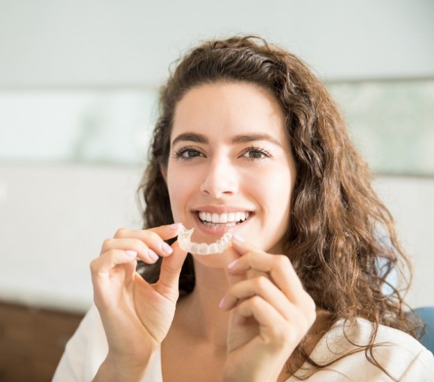 Woman with curly hair holding Invisalign