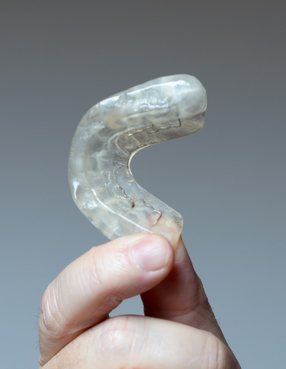 Hand holding off white occlusal splint tray