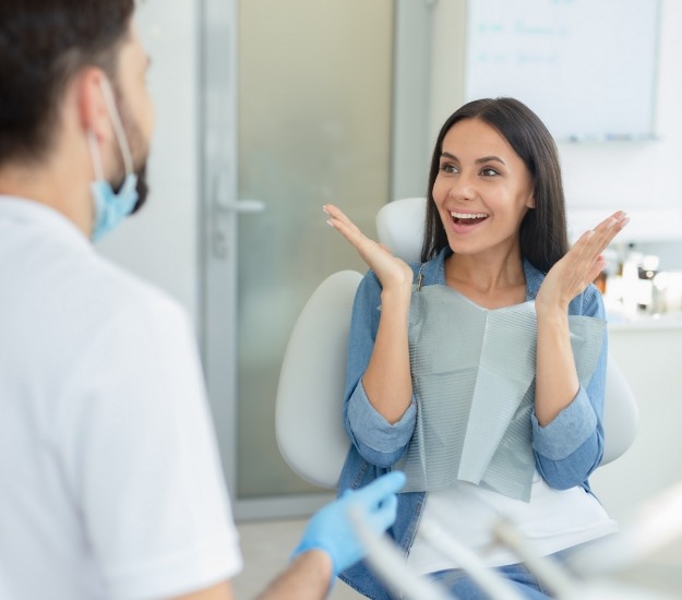 Patient in dental chair smiling at her dentist