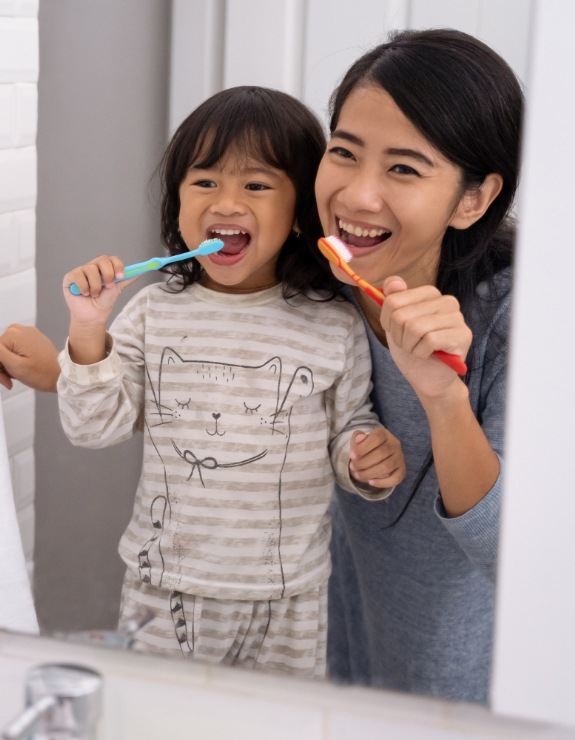 Mother and daughter brushing their teeth together