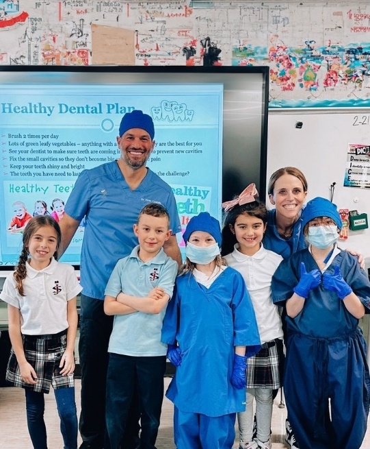 Arlington Heights dentist holding dinosaur plush while giving presentation to classroom