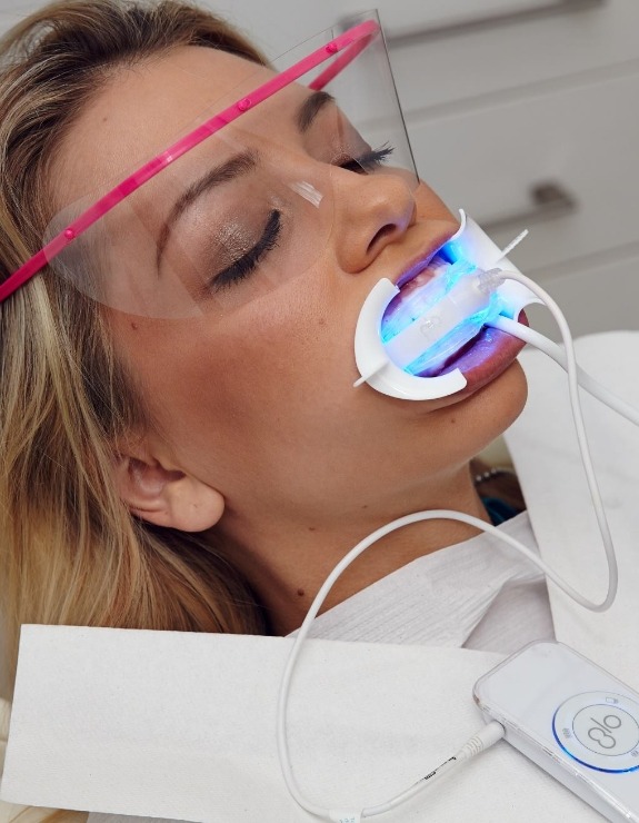 Woman in dental chair receiving professional teeth whitening