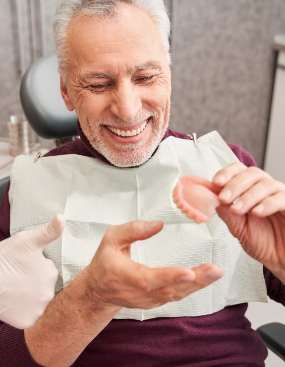 Senior dental patient looking at a denture