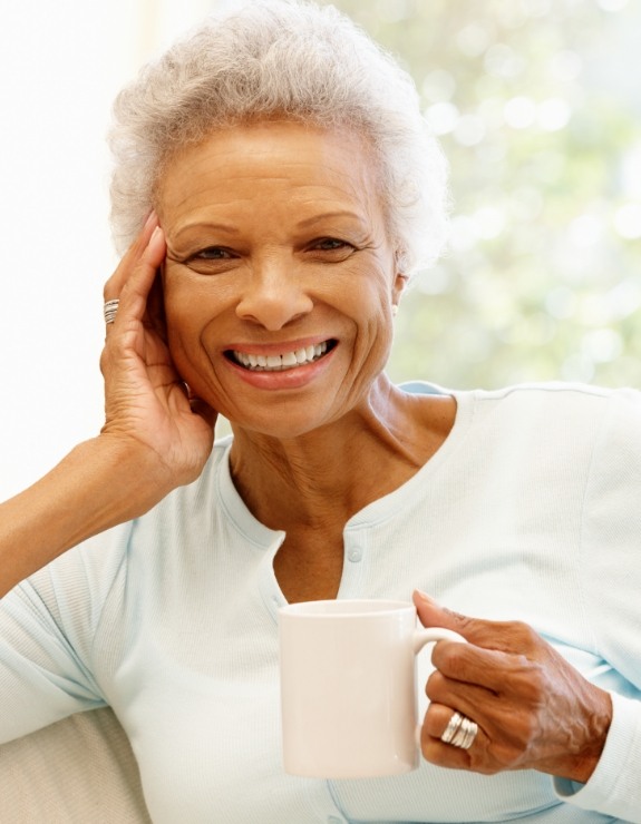 Smiling senior woman holding a white coffee mug