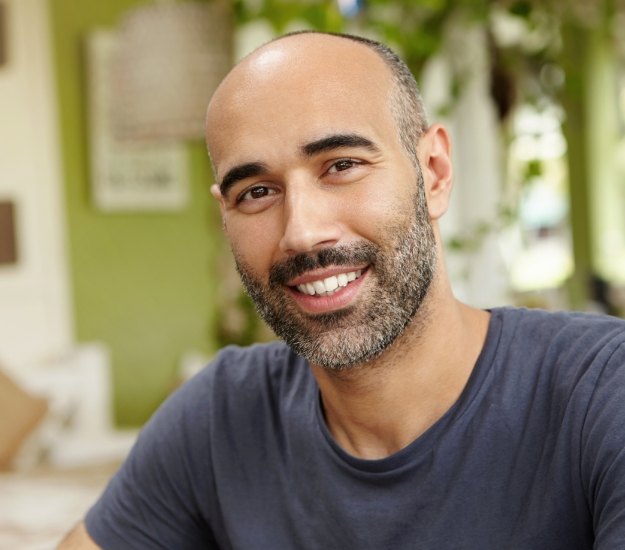 Man in dark gray tee shirt smiling outdoors