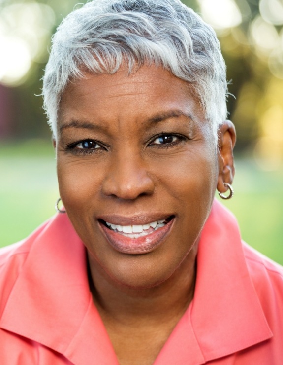 Woman in orange buttoned shirt smiling outdoors