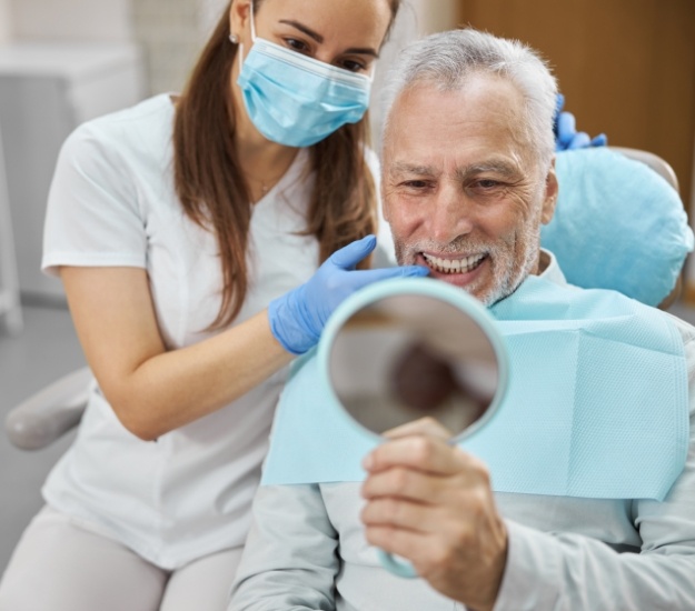 Senior dental patient admiring his new smile in mirror