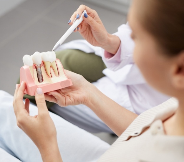 Dentist showing a dental implant model to a patient