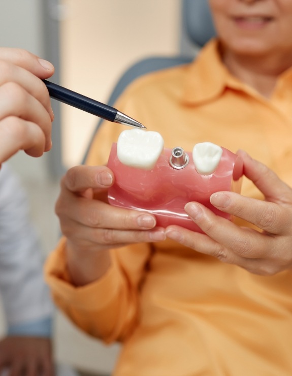 Dentist showing a model of a dental implant to a patient