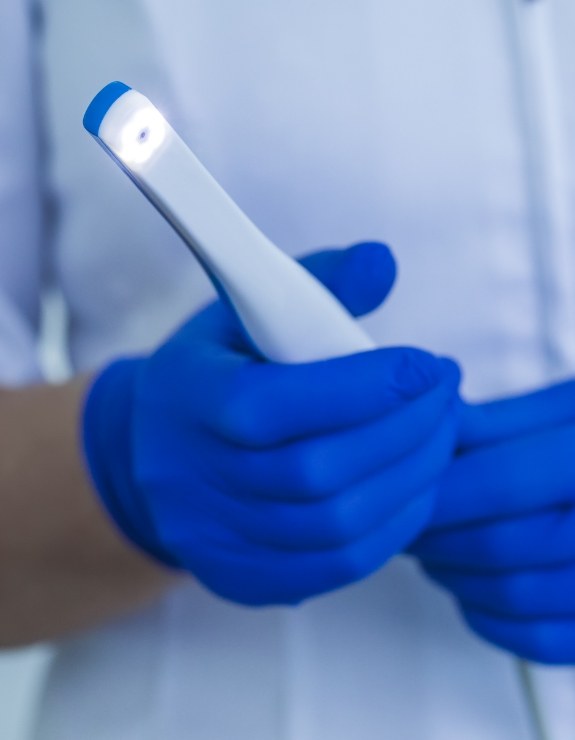 Gloved hands holding a thin white intraoral camera