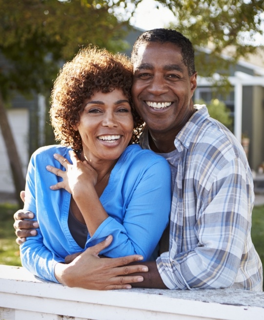 Man and woman smiling outdoors with dentures in Arlington Heights