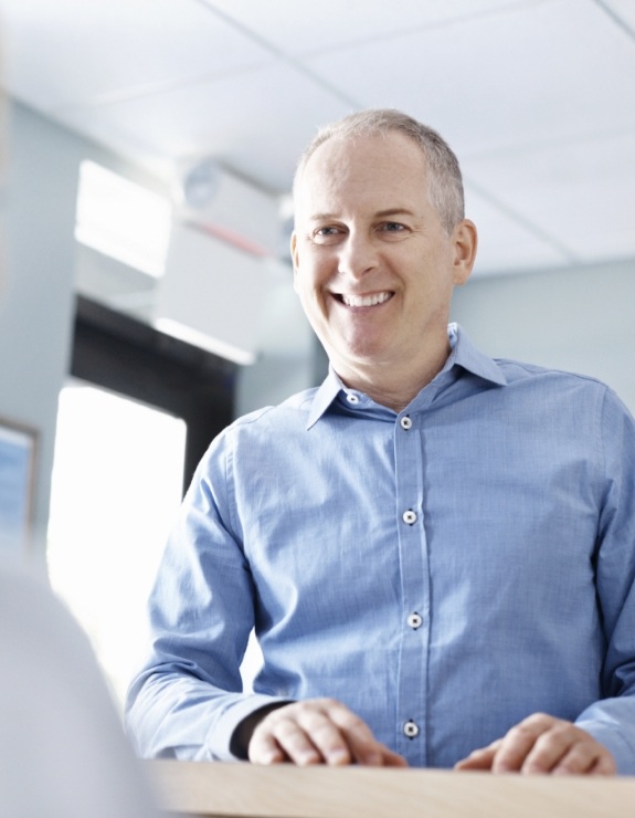 Man smiling at dental office receptionist