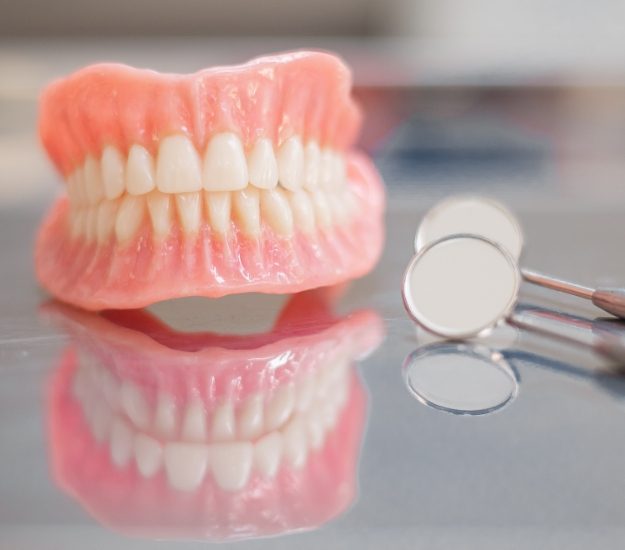 Full dentures on table next to dental mirror