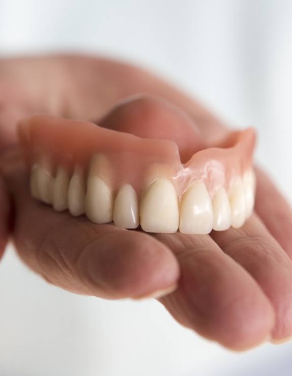 Hand holding a full upper denture