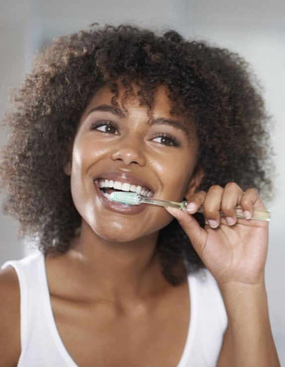 Woman smiling while brushing her teeth