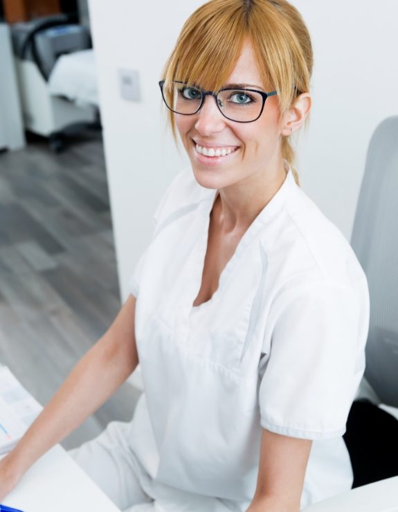 Smiling dental team member sitting at desk