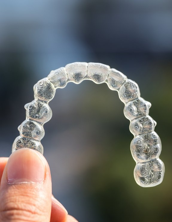 Close up of hand holding an Invisalign aligner