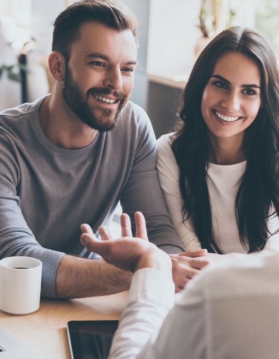 Man and woman smiling at person across table