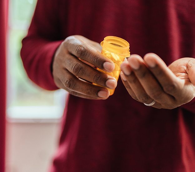 Hands of someone in red shirt holding prescription pills