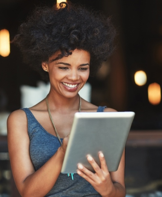 Woman smiling while looking at tablet