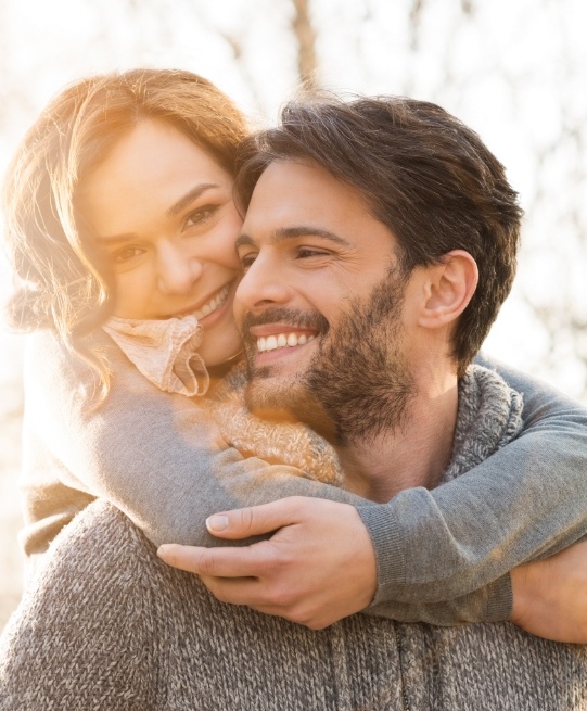 Man and woman grinning on sunny day after smile makeovers in Arlington Heights