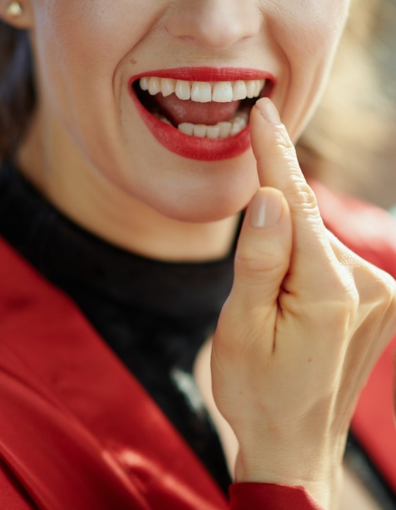 Woman with red lipstick looking at her smile in mirror