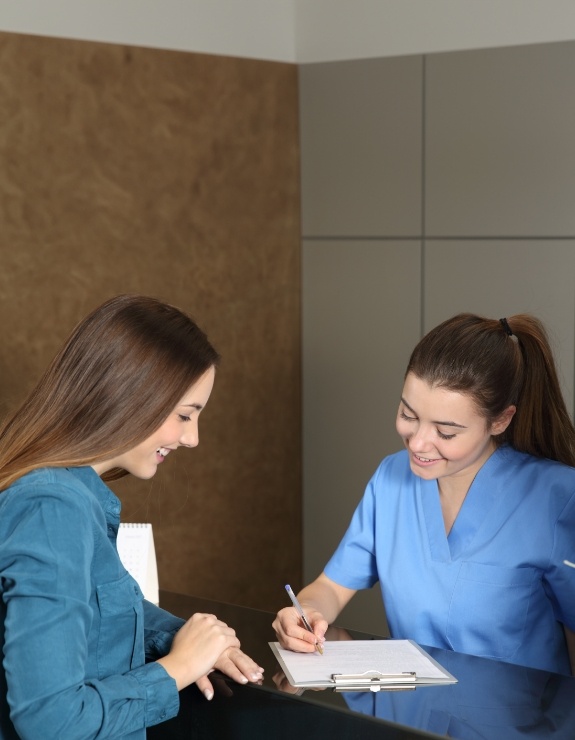 Dental team member showing a patient where to sign on clipboard