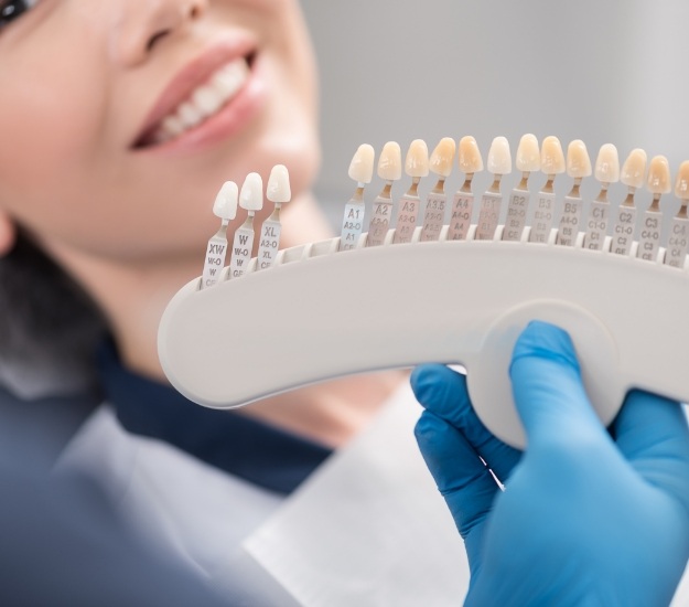 Dentist holding shade guide in front of a smiling patient