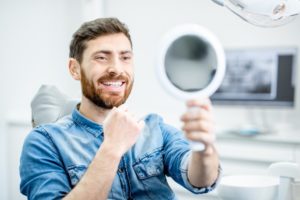 man admiring his smile after getting cosmetic dental flaws fixed 