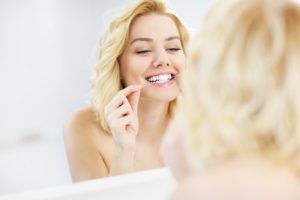 person looking at mouth in bathroom mirror 