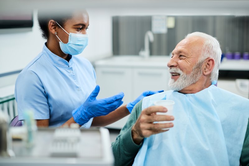 elderly patient smiling while speaking with cosmetic dentist