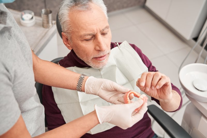 A dentist holding dentures for a patient