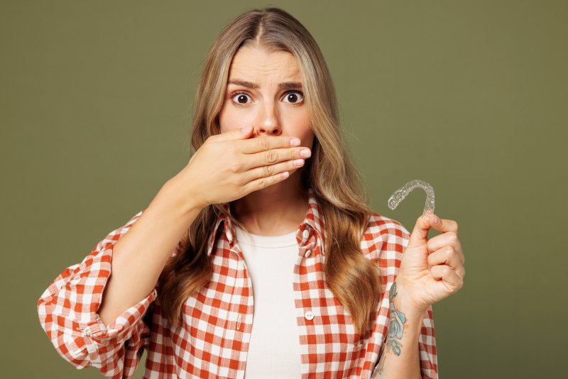 Patient covering their mouth while holding a mail-in clear aligner